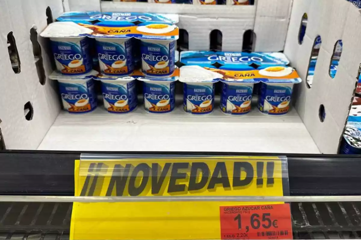 Foto de un estante de Mercadona que tiene una caja y dentro hay tres packs de yogures griegos azúcar de caña con el cartel abajo de "Novedad" y el precio de 1,65 euros