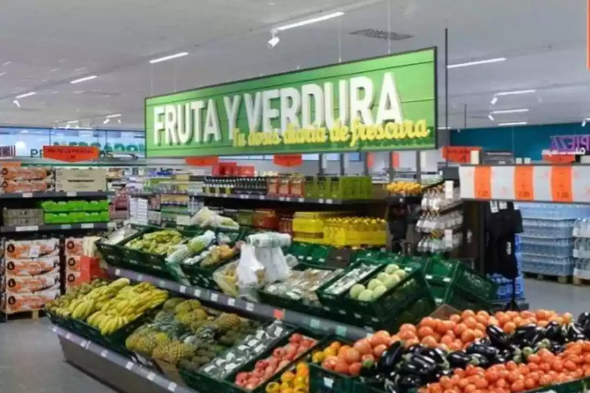 Foto de un supermercado y en concreto su zona de Fruta y Verdura con un gran carte y cajas de fruta en el centro