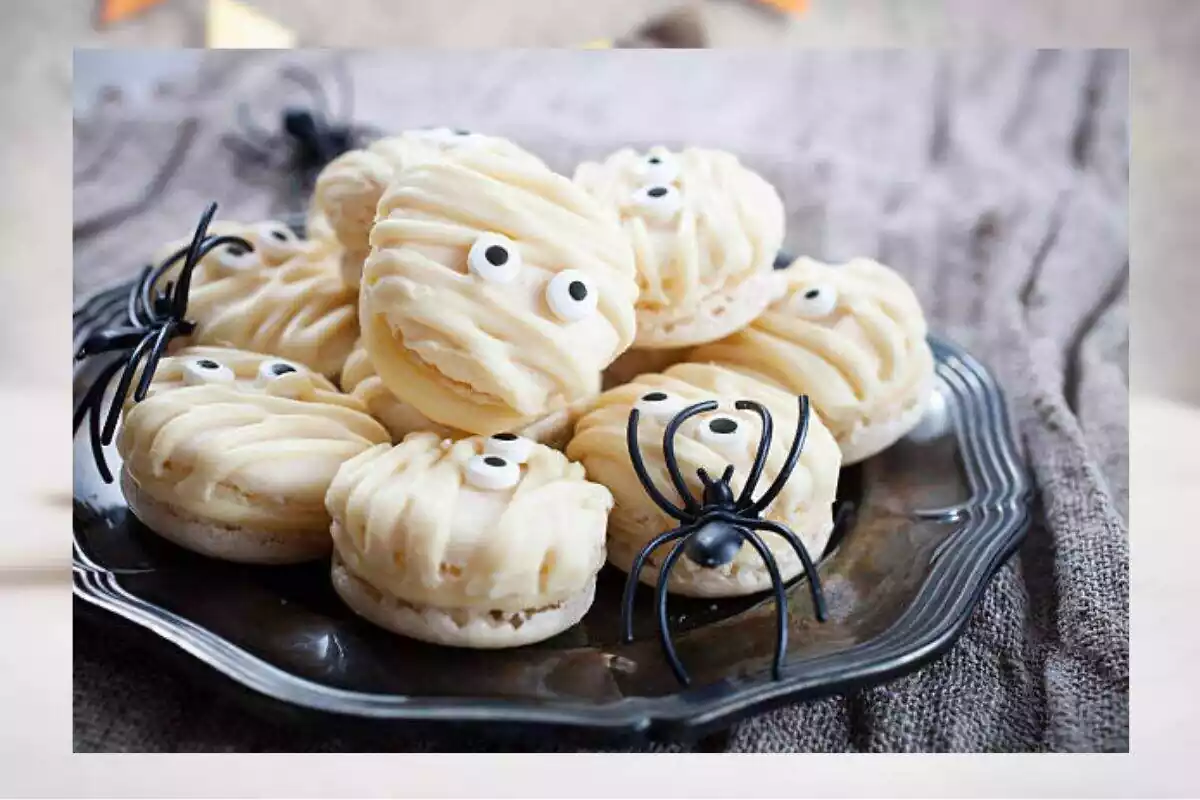 Foto de unas galletas oreo envueltas en fondan con ojos y como si fueran momias en un plato con arañas de plástico. Detrás una foto desenfocada Foto de unas galletas oreo envueltas en fondan con ojos y como si fueran momias en un plato con arañas de plástico. Detrás una foto desenfocada